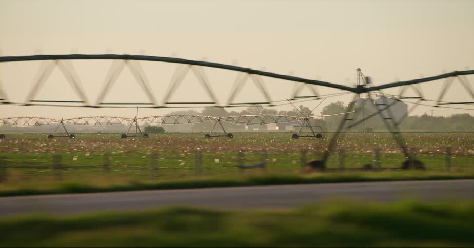 Semi truck drives along highway passing a commercial farm