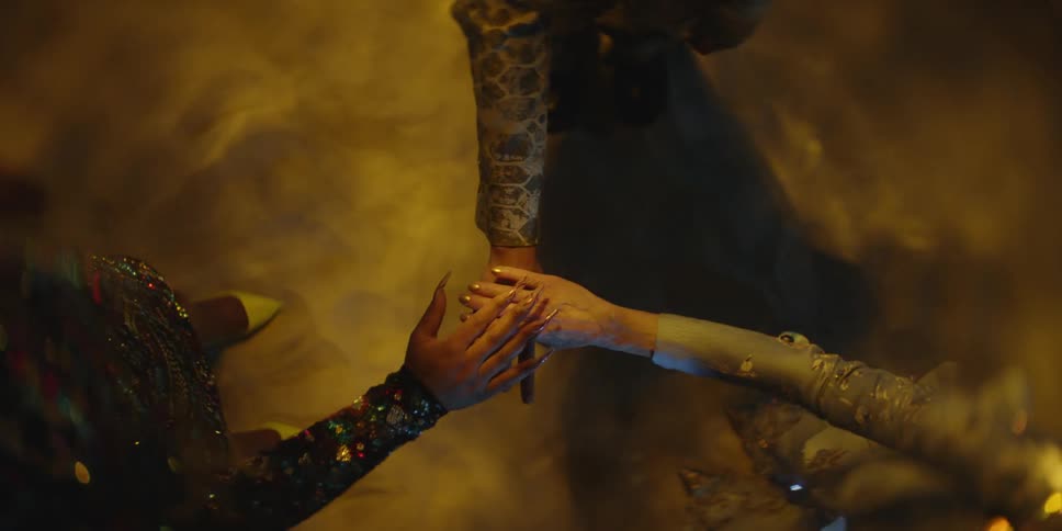 Three women stand in a circle and stretch their arm out to the middle and clasp their hands