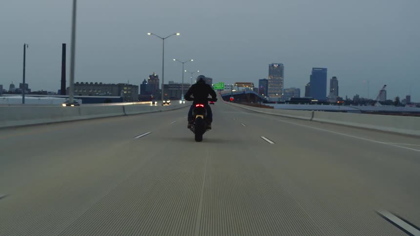 A motorcycle is traveling on a freeway towards downtown