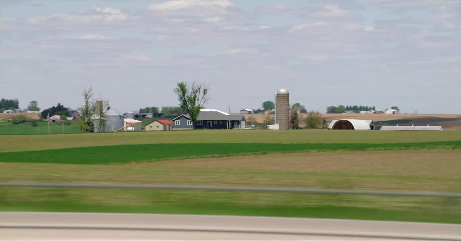 Cars are driving on a road near a farm in spring