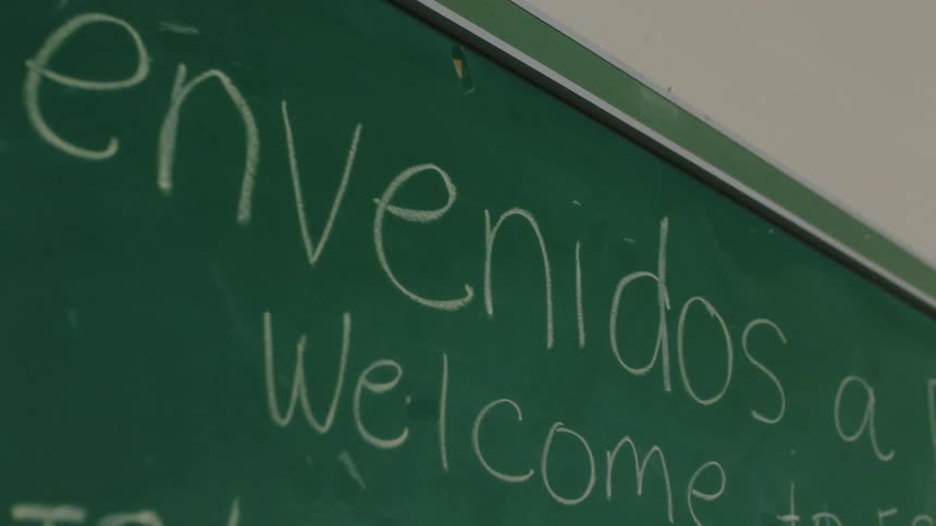 A welcome message on the chalkboard written in english and spanish welcomes people to a esl class