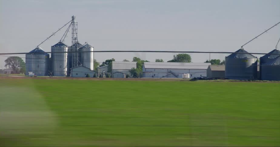 Cars are driving on a highway near a rural farm