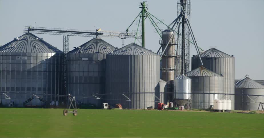 A number of storage tanks and silos stand clustered together on commercial farm