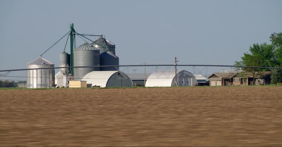 Cars are driving on a highway near farmland