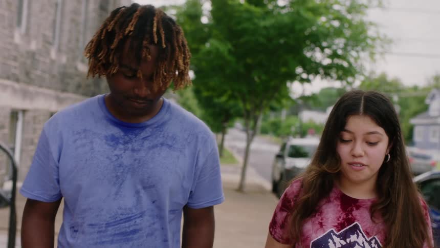 Two friends talk to each other while walking on a small town street at daytime