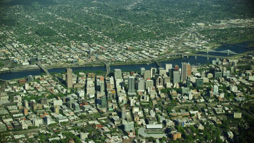 Daytime aerial of downtown Portland as seen from high above as the camera flies over downtown buildings and the Willamette River
