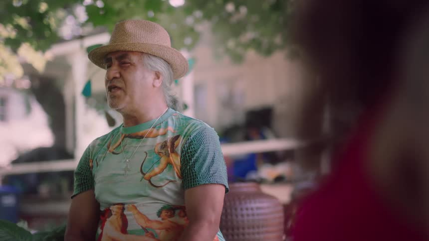 A man is sitting outdoors and talking to friends