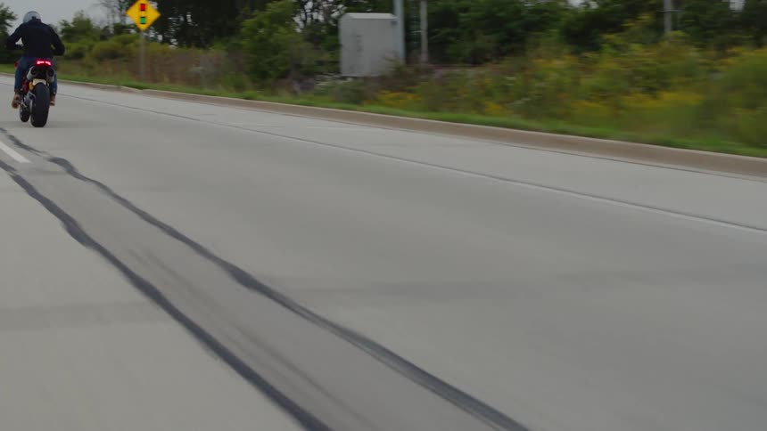 A motorcycle is traveling very fast as it approaches a curve in the road