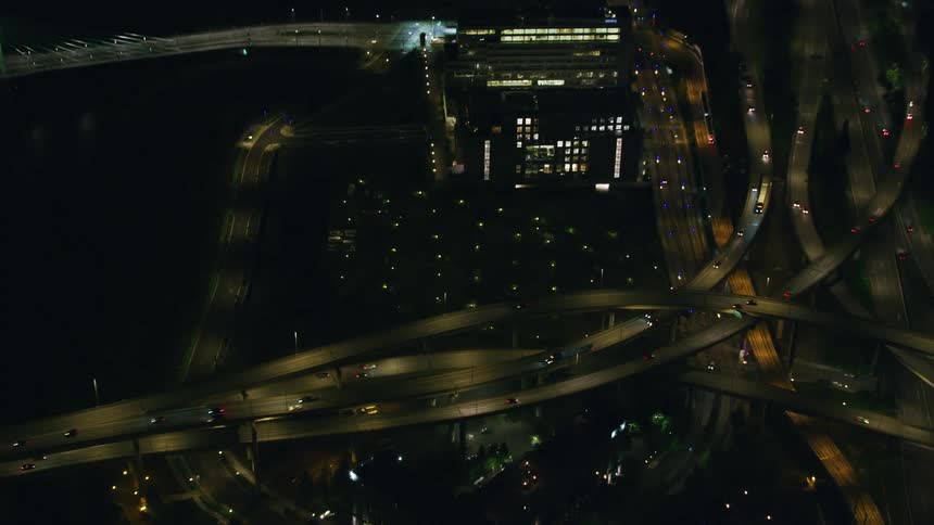 Night aerial of a busy network of highway bridges over Portland Oregon as many bridges pass over and curve around others