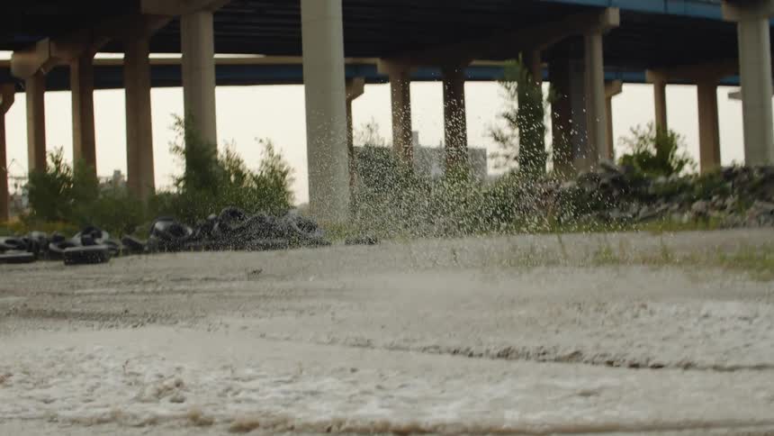 A person is driving a motorcycle through a puddle of water