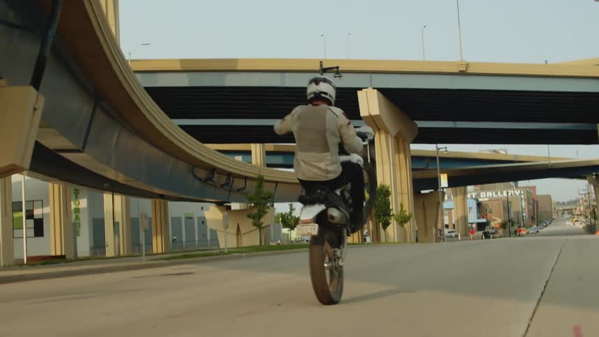 A man is riding a motorcycle on a highway in a city