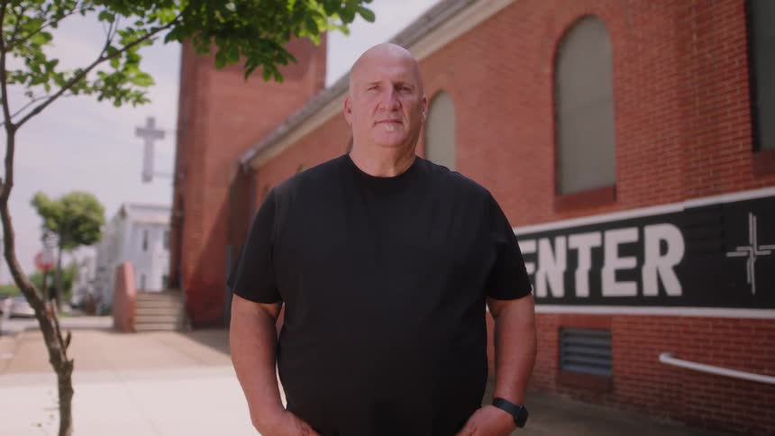 A man is smiling and standing outside of a building