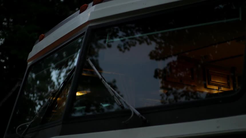 A large windshield is clean and reflecting the trees around