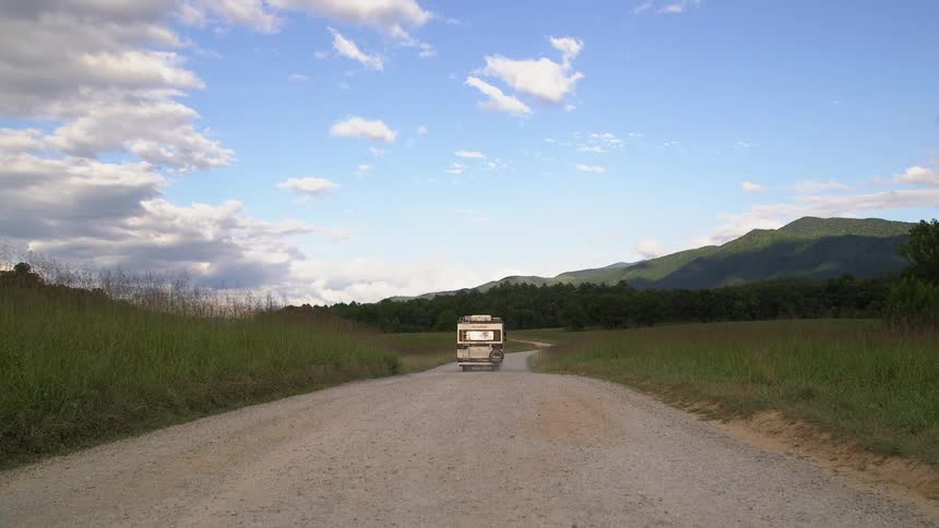 An rv driving along a dirt road near the mountains