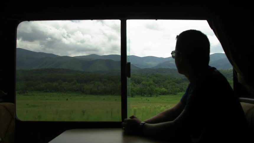Man rides in an rv and looks out at a rural area