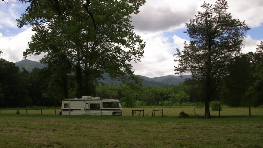 A recreational vehicle drives by a green field
