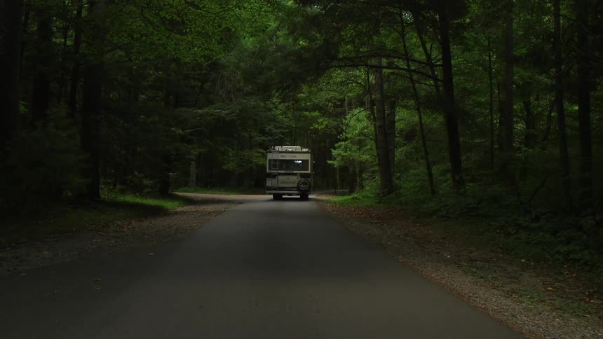 An rv driving through a forest