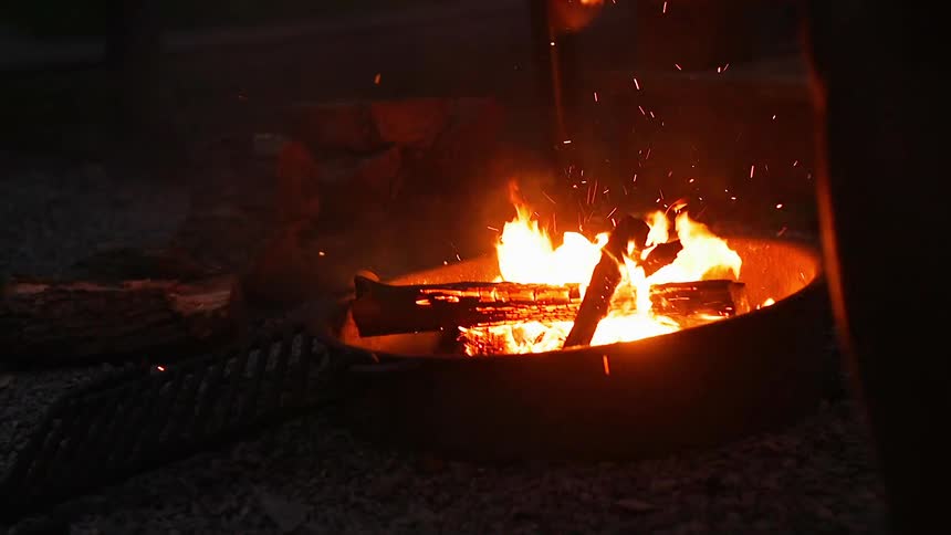 A person fans a fire at night