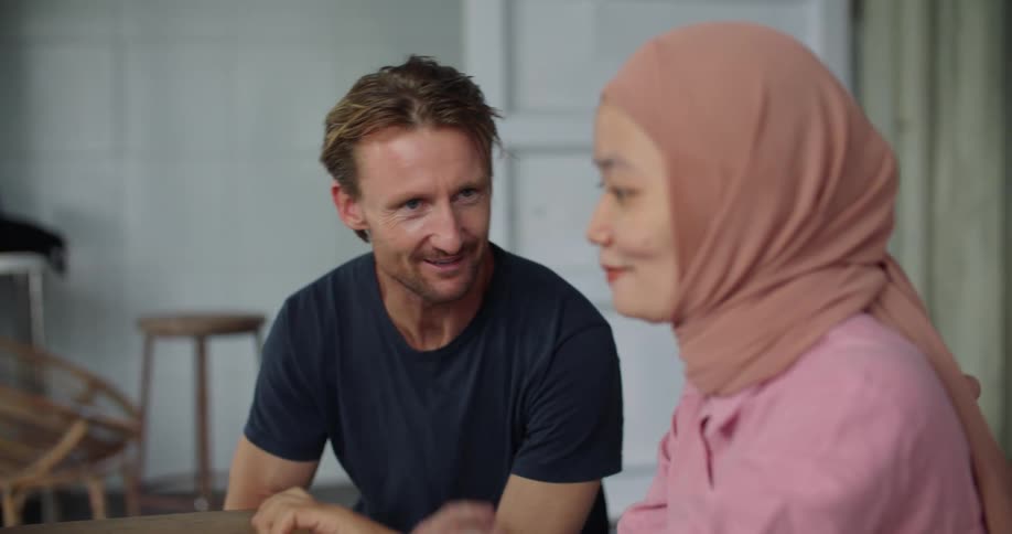 Man and woman laugh and talk while looking at computer screen