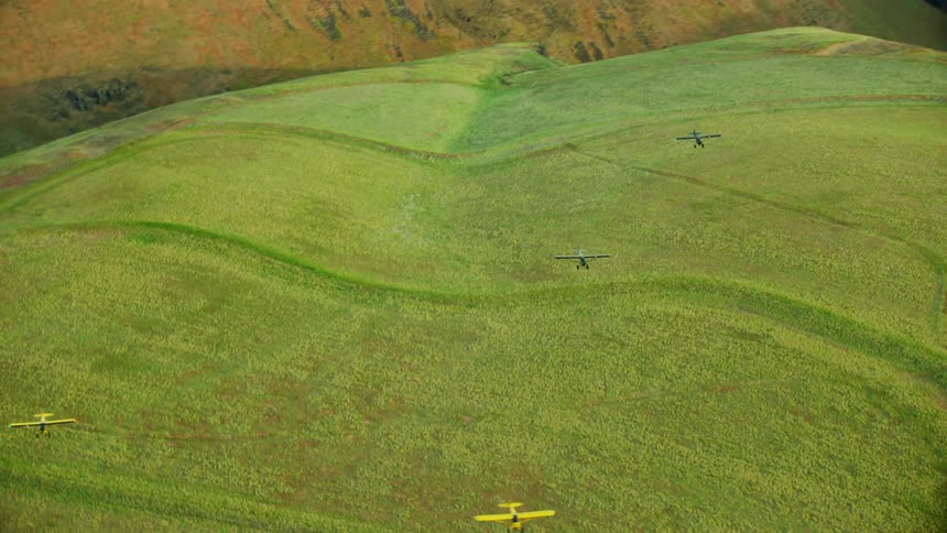 Aerial view of light aircrafts flying over green mountains as seen from high above