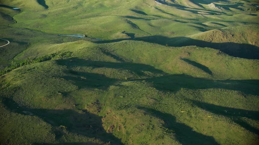 Group of backcountry aircraft fly over hill country near flowing river in the spring season