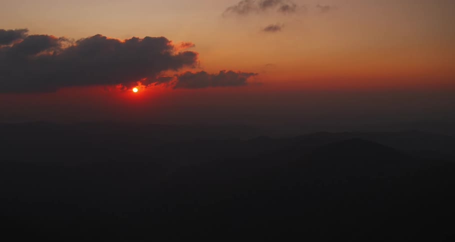 Aerial view of the sun setting on the horizon on a red sky at evening