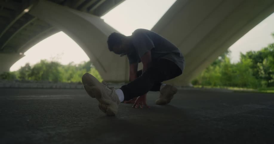 Man wearing sunglasses stretches out under a highway at daytime