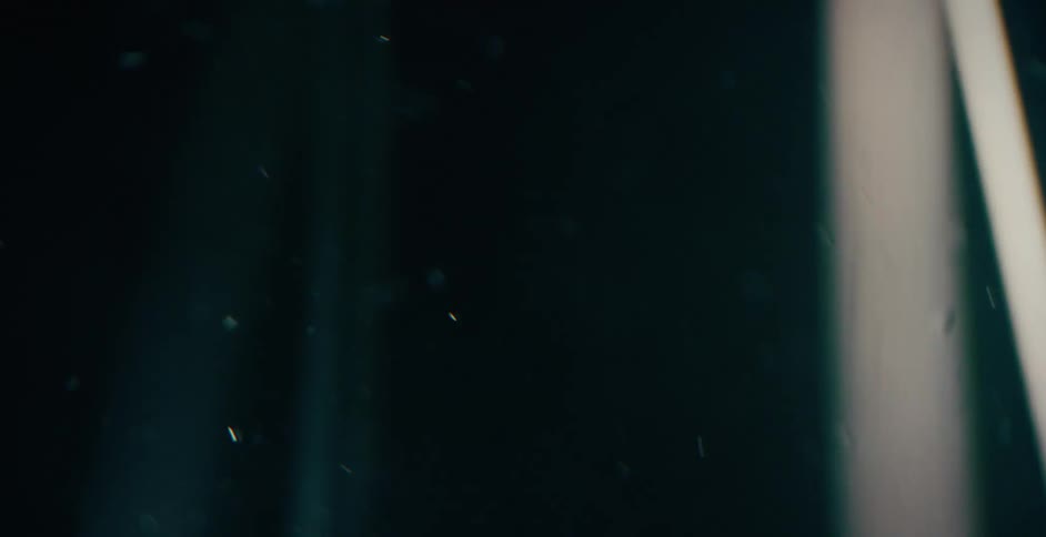 Spinning ribbons of light with floating bubbles against a black background