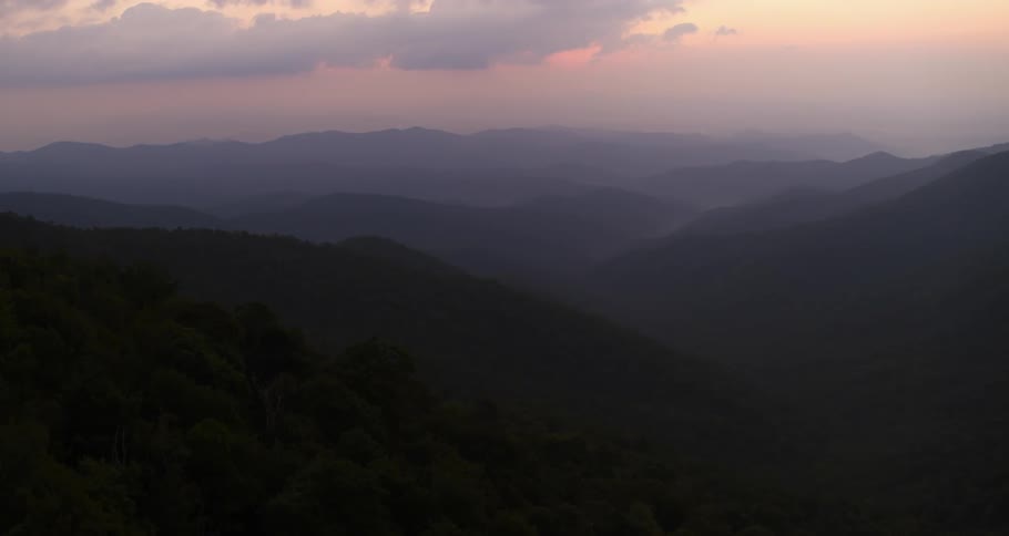Aerial view of mountain slope being silhouetted against the sky at sunset