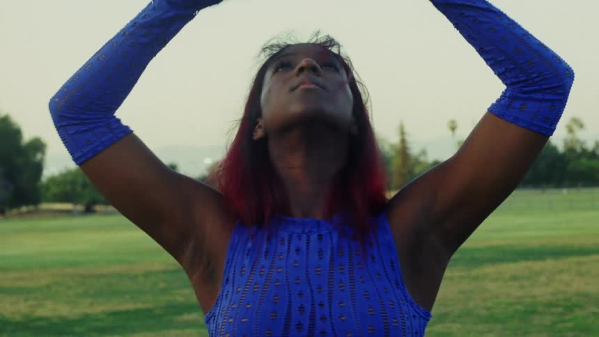 Young woman with red hair dances on a park at morning caught on vintage film