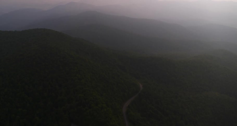 A road winds up a mountain in the fog