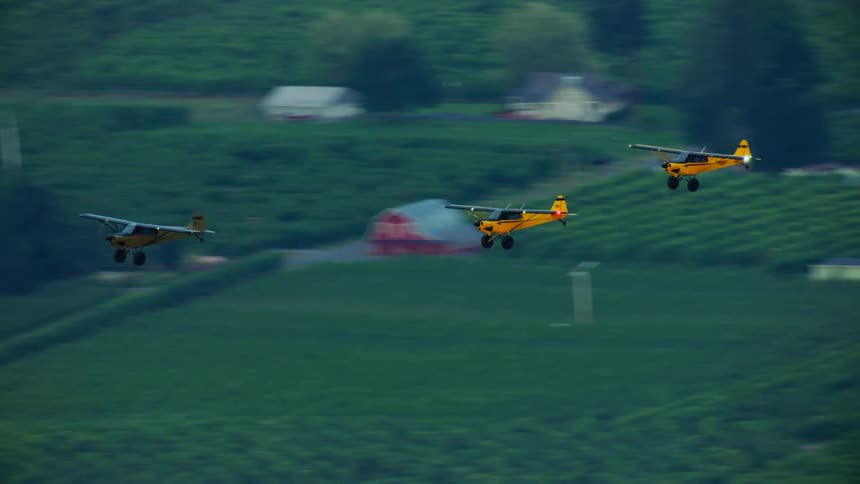 A group of backcountry aircraft fly together over a rural countryside during the early morning light