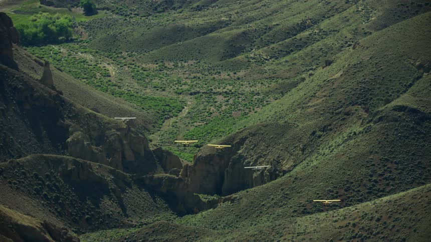 A group of backcountry airplanes fly over a desert canyon