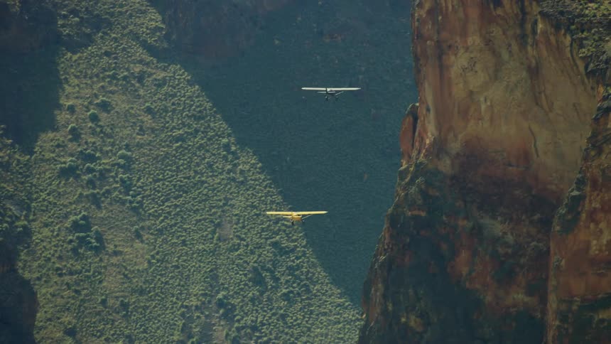 Two small backcountry airplanes fly into a craggy and remote desert canyon in the wilds of Idaho