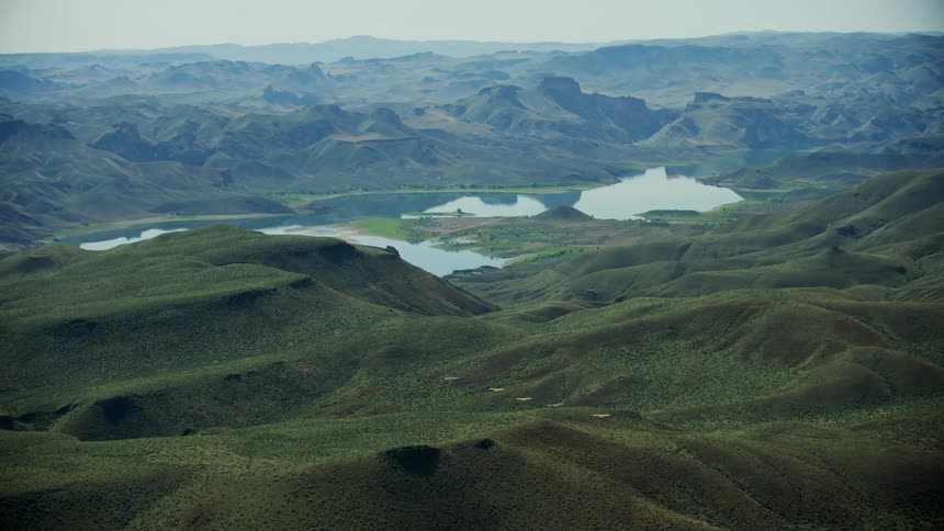 Aerial view of light aircrafts flying over green mountains next to lake