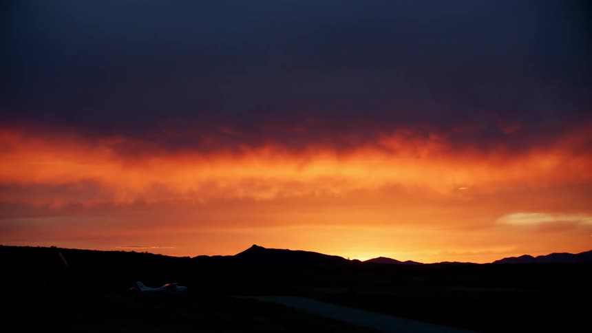 The orange sunlight is disappearing from the skyline making all the clouds light up in reddish yellow golden hues
