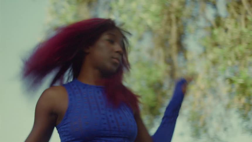 Female dance with red dyed hair dances outdoors