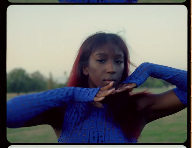 Woman wearing electric blue fingerless gloves and matching top moves through poses while standing in field