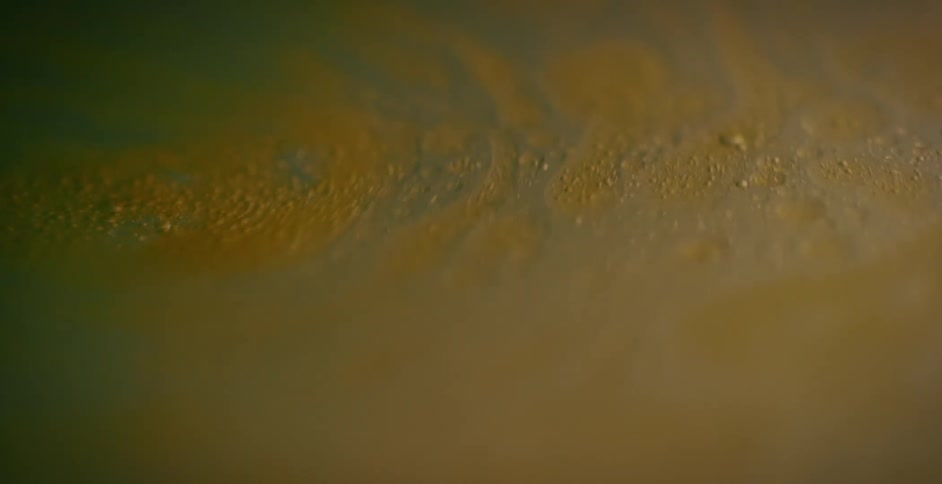 A thick brown liquid is swirling as it moves and bubbles rise to the top