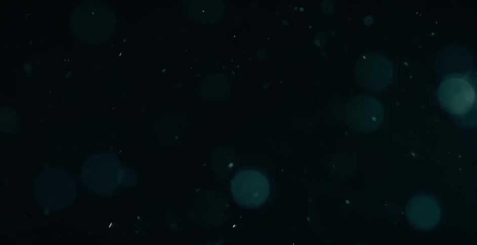 Particles of dust float upward in a dark space