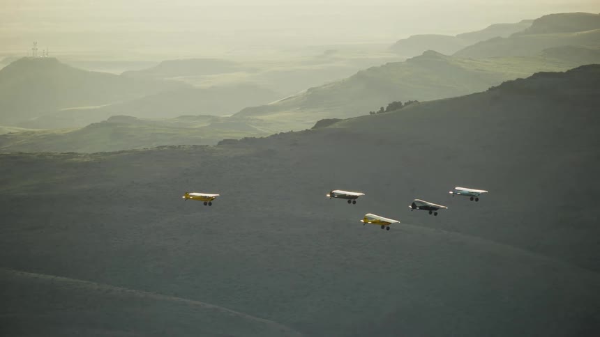 Five small backcountry airplanes fly over the mountains on a misty summer evening