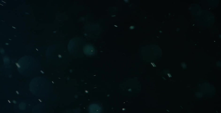 Small bubbles are floating in the air and a bright light shines across the darkness