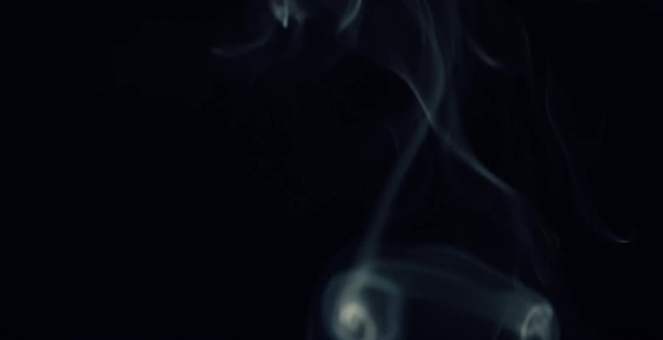 Smoke swirls and rises against a black background