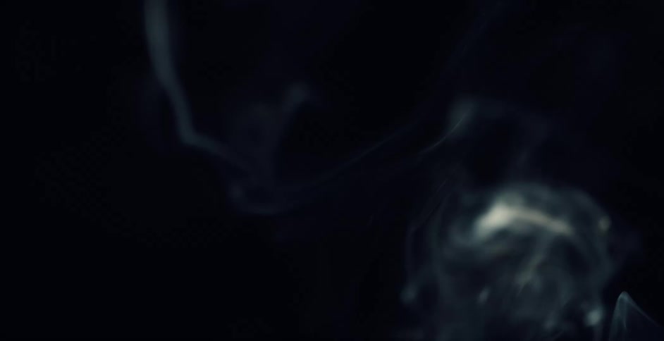 White smoke swirls as it rises through the dark