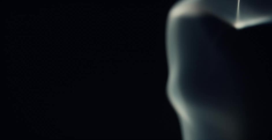 Light illuminates wisps of smoke floating in the darkness