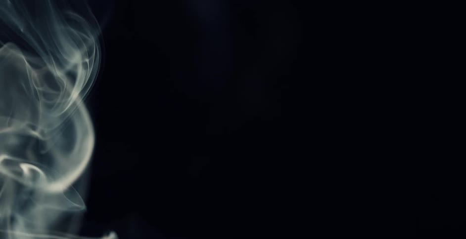 Light illuminates wisps of smoke floating in the darkness
