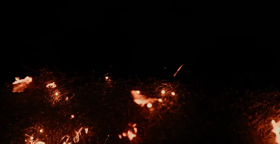 Bright orange fire and sparks flow around curling wire and fade to black