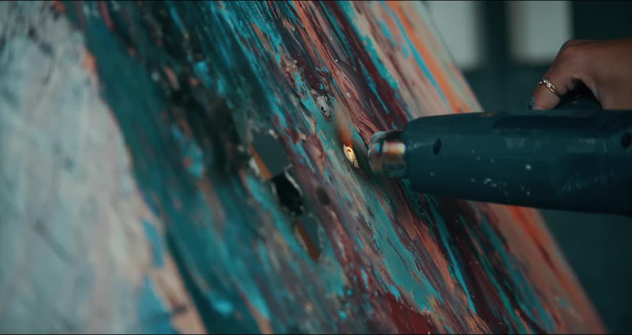 Painter holds a heat gun close to a painting and ignites a flame