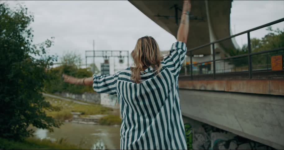 Woman dances on the side of a road and turns and smiles
