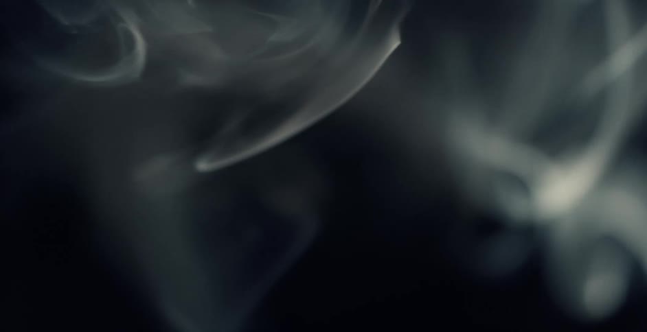 Whisps of white smoke swirling in the air in front of a black background